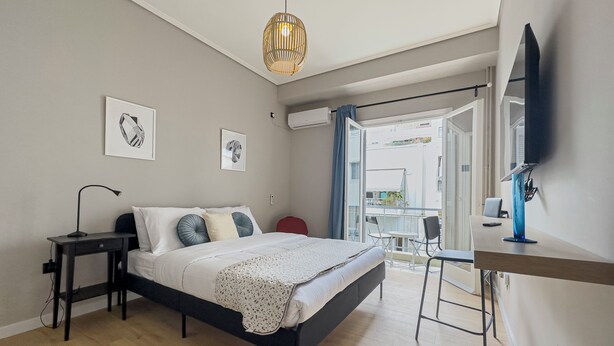 Ein Schlafzimmer mit Bett, Nachttisch, Lampe und Blick ins Freie.