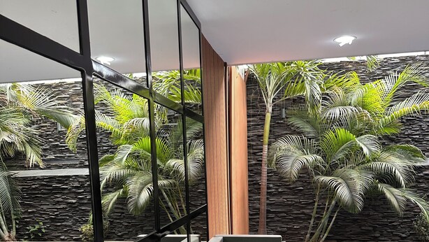 Een modern interieur met uitzicht op het zwembad, met een bank en houten tafels.