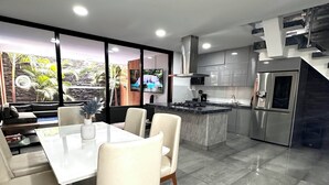 Een moderne keuken met een centraal eiland, roestvrijstalen apparatuur en een groot raam met uitzicht op een tropische tuin.