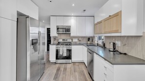A modern kitchen with stainless steel appliances, white cabinetry, and a wooden countertop.