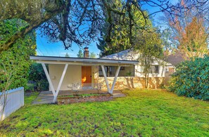 A single-story house with a covered porch, a brick chimney, and a well-maintained lawn. - 3BR Seattle Home w/ Spacious Yard | Near Northgate (Seattle)
