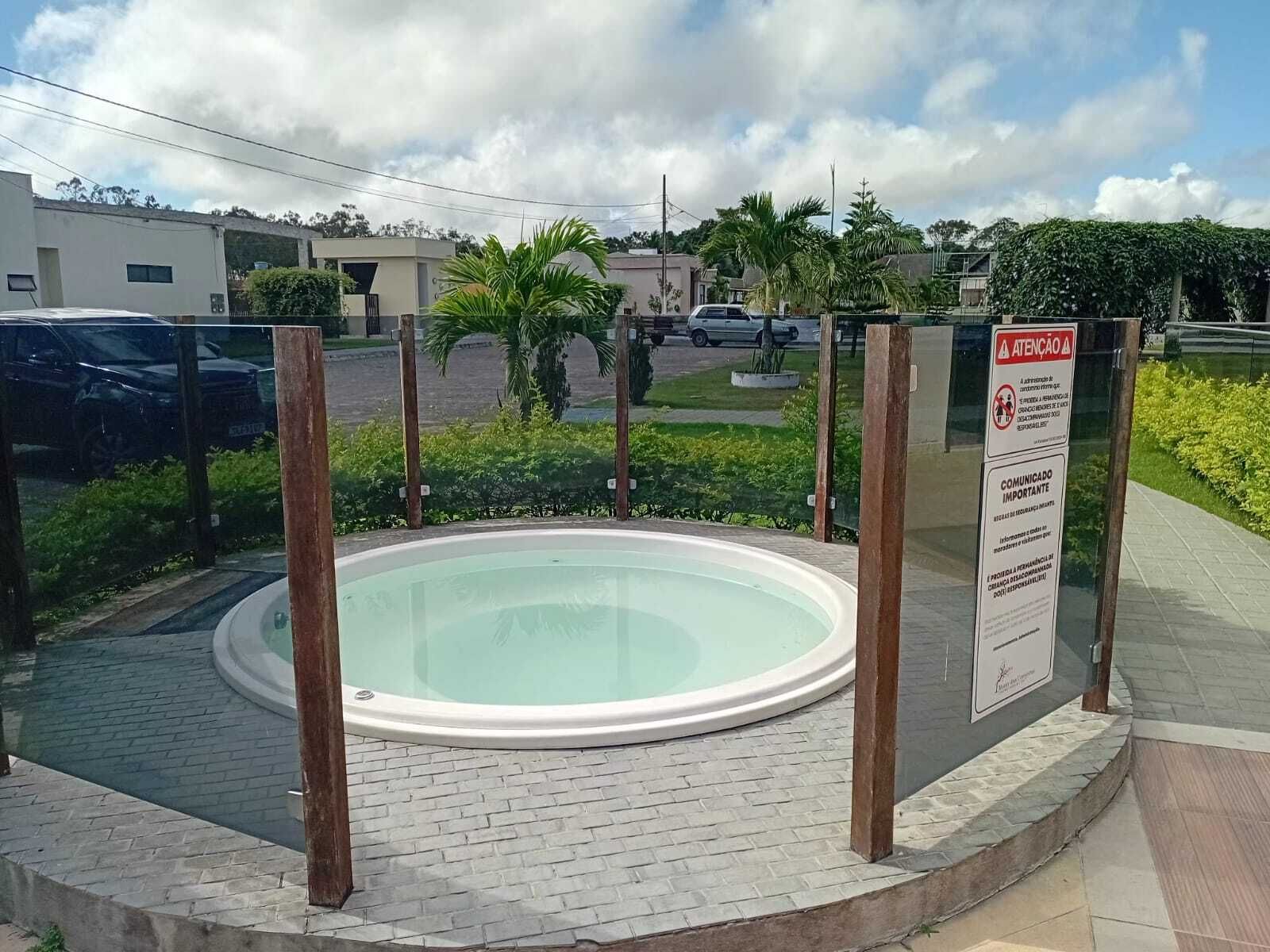 A circular pool with a wooden fence, surrounded by a paved area with a brick pattern.