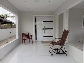 A clean, modern room with white walls, a tiled floor, a white door with black horizontal lines, and two wooden chairs. - House with 6 bedrooms, 4 suites, 2km from the center.  (Bananeiras)