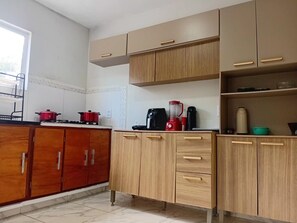 Une cuisine avec des meubles en bois, une cuisinière à gaz et divers appareils de cuisine.