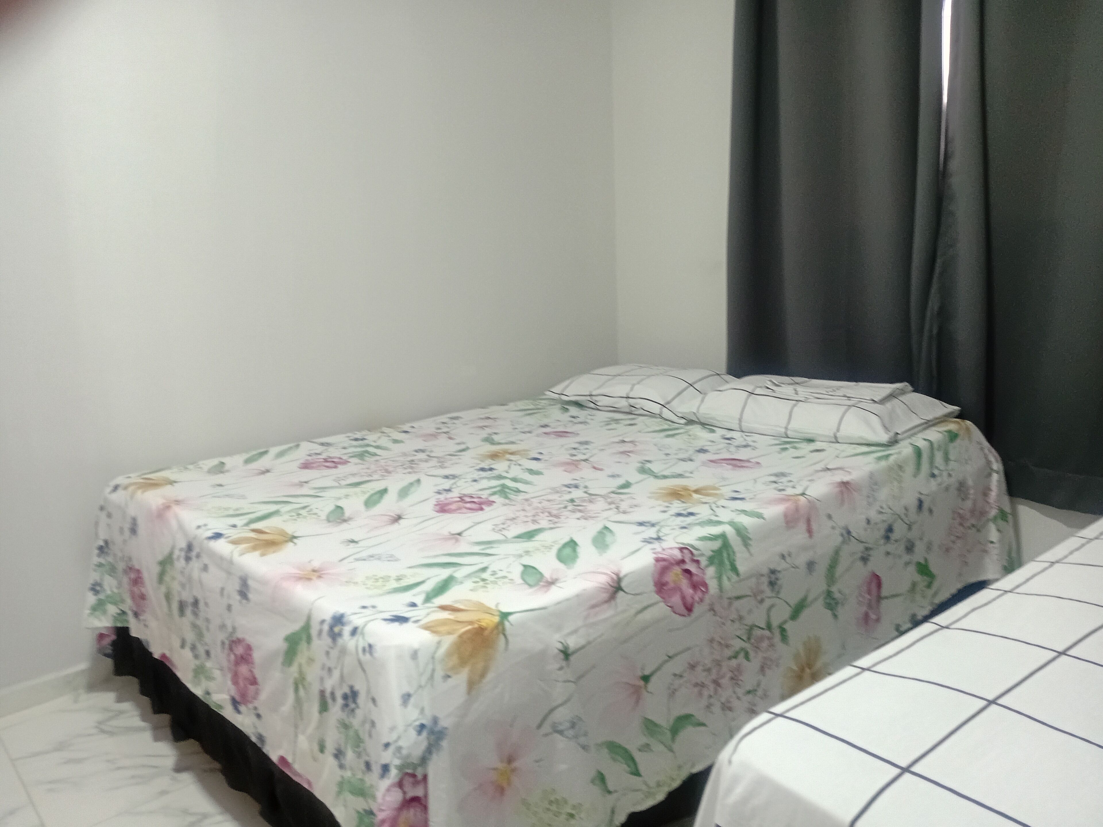 Una habitación pequeña con cama individual, colcha estampada y ropa blanca sencilla.