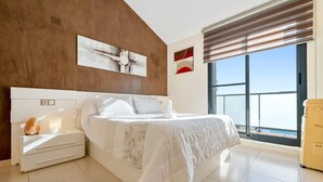 A modern hotel room with a large bed, a nightstand, a water feature, and a large window with a view.