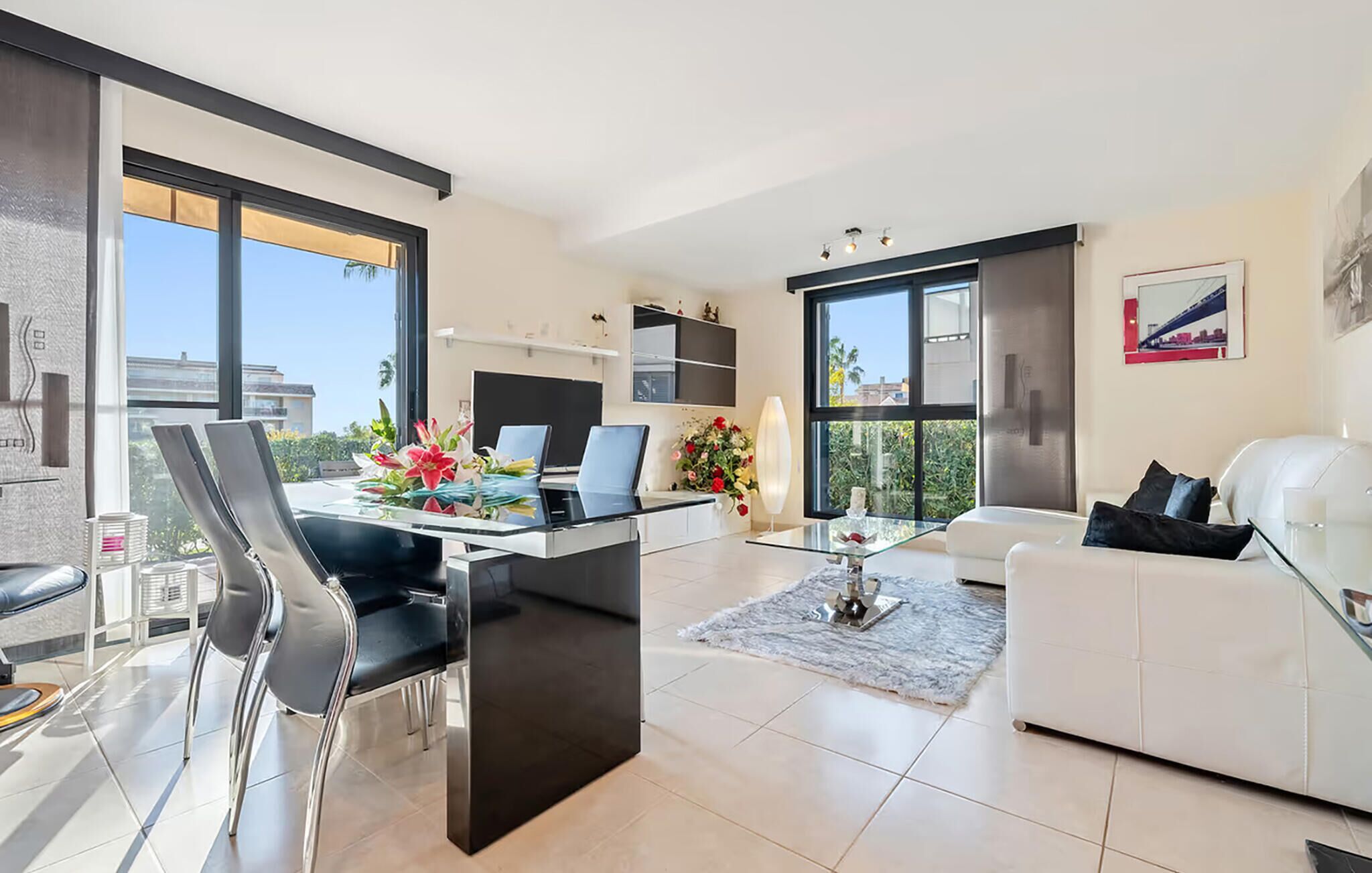Una sala de estar moderna con comedor, ventanas grandes y vista a la ciudad.