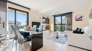A modern living room with a dining area, large windows, and a view of the city.