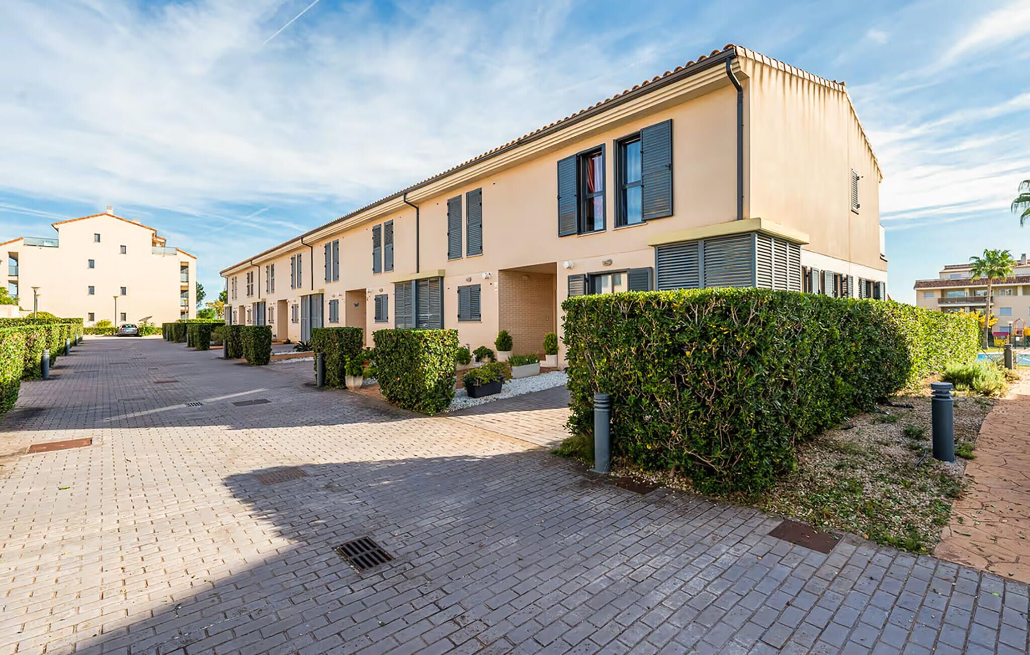 A modern apartment building with a paved driveway and well-maintained hedges.
