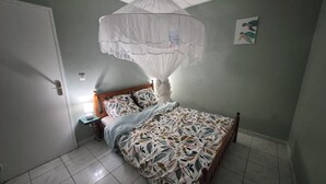 A bedroom with a bed, a nightstand, a bedside lamp, a white canopy, and a wall art piece.