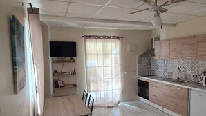 A spacious kitchen with a dining area, a ceiling fan, and a TV mounted on the wall.