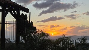 A sunset view with a wooden pergola and palm trees.