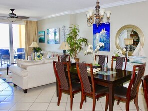 A dining area with a dark wooden table, six chairs, and a chandelier. - Tropic Winds 905 (Panama City Beach)