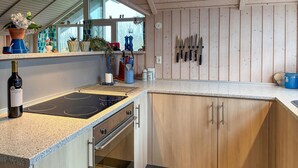 Une cuisine équipée d’une cuisinière intégrée, de meubles de rangement en bois et d’un plan de travail sur lequel sont disposés divers objets.