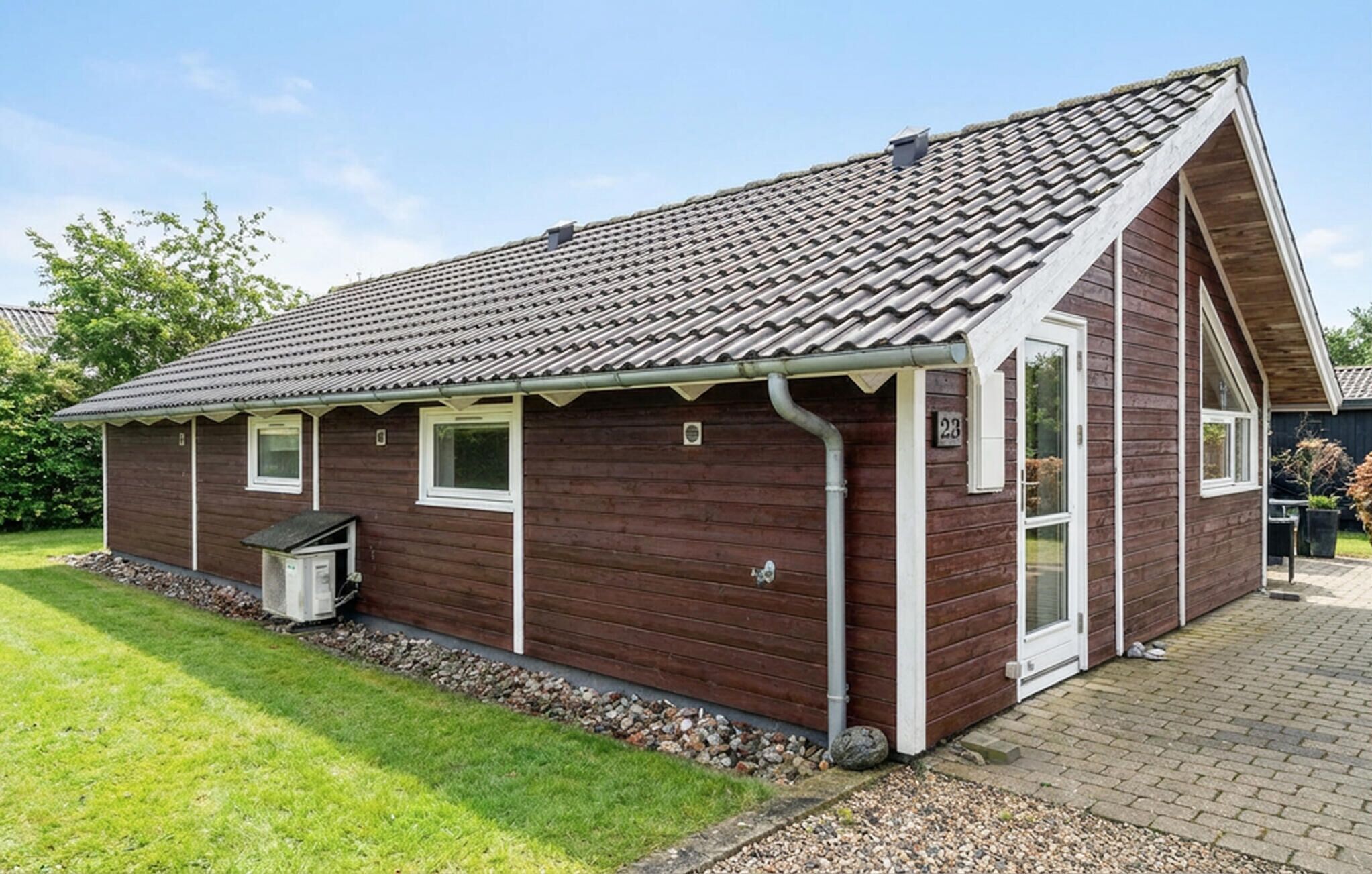 Ein einstöckiges Holzhaus mit Ziegeldach, einer kleinen Veranda und einem Schild mit der Nummer 28.
