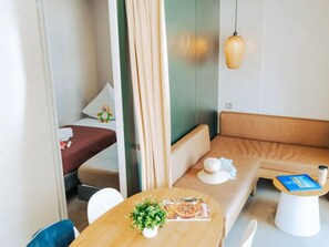 Ein modernes Hotelzimmer mit Bett, einer Couch, einem kleinen Tisch mit einer Zeitschrift und einer Pendelleuchte.