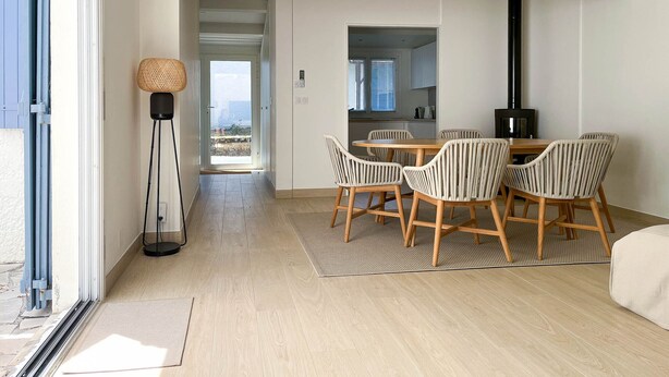 A modern dining area with a wooden table and striped chairs, a black stove, and a view through a glass door. - Renovated Villa in La Palmyre - Sleeps 6 - Air Conditioning - Wifi - Parking (La Palmyre)