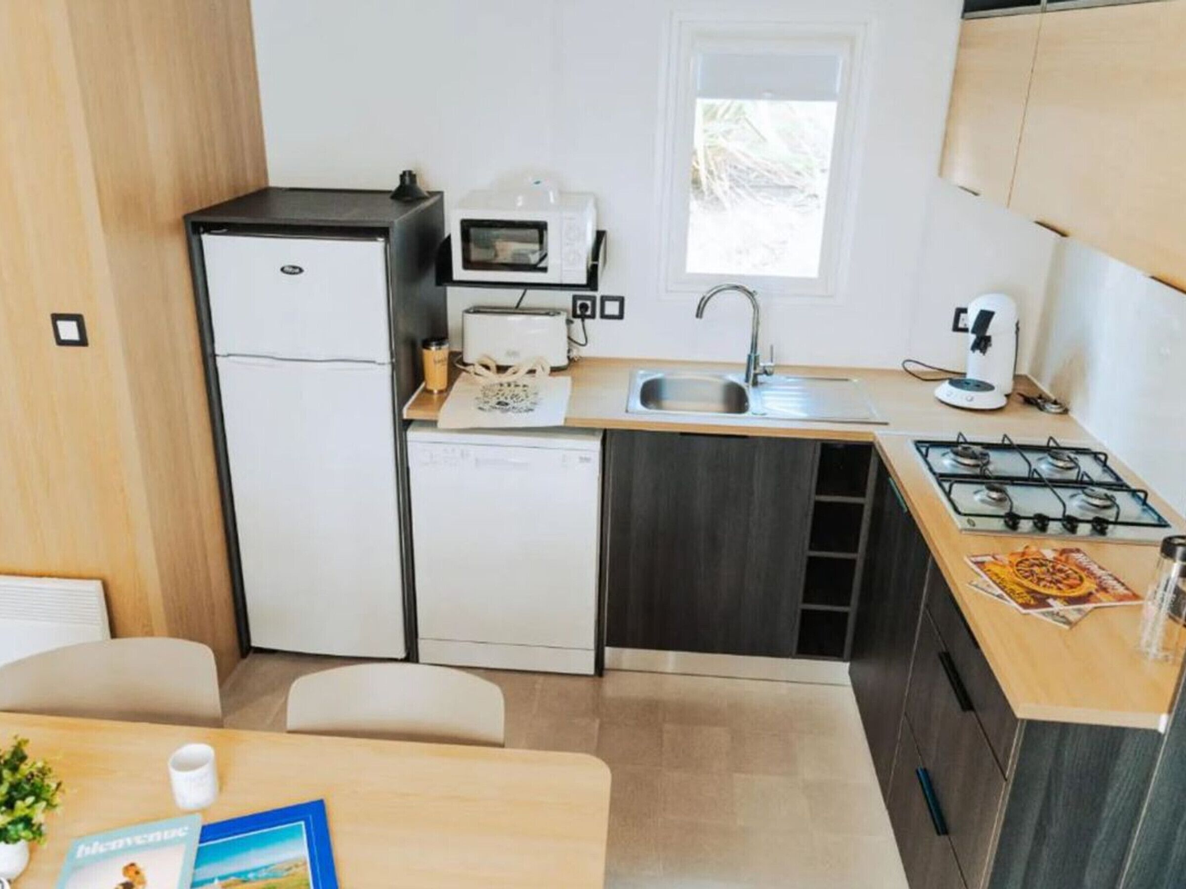 A compact kitchen with a refrigerator, microwave, toaster, sink, and stove.