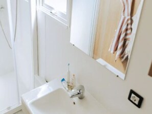 Un baño con un lavabo blanco, un espejo y una toalla colgada en la pared.