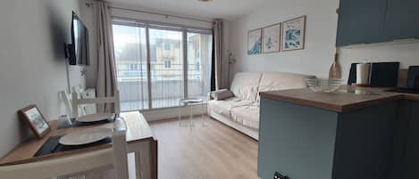A modern apartment with a dining area, a sofa, and a kitchen.
