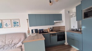 Een moderne keuken met blauwe kastjes, een houten aanrechtblad en een inbouwoven.
