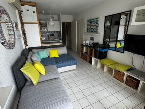 A compact living space with a sofa, a television, a kitchen area, and a dining table. - Air-Conditioned Apartment with Private Parking - Argelès-sur-Mer - 4 people (Argelès-sur-Mer)