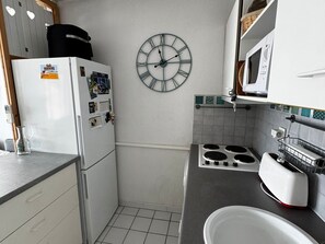 A compact kitchen with a refrigerator, stove, microwave, and a wall clock. - Air-Conditioned Apartment with Private Parking - Argelès-sur-Mer - 4 people (Argelès-sur-Mer)