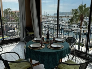 A dining area with a table set for four, overlooking a marina with boats.