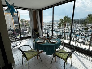 A balcony with a table set for dining, overlooking a marina with boats and palm trees. - Air-Conditioned Apartment with Private Parking - Argelès-sur-Mer - 4 people (Argelès-sur-Mer)