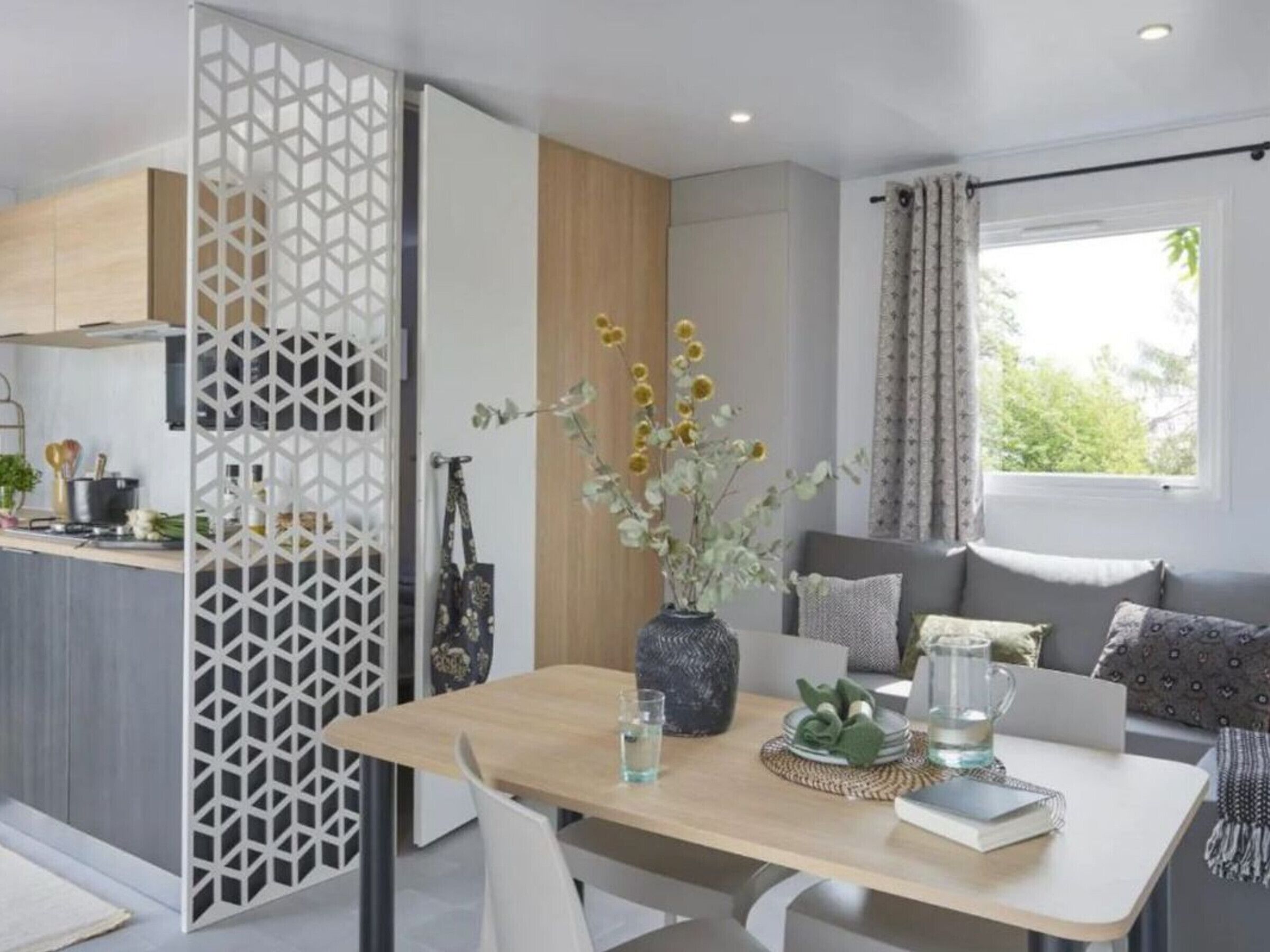 Una sala de estar moderna con una mesa de comedor de madera, un sofá y un jarrón decorativo con flores.