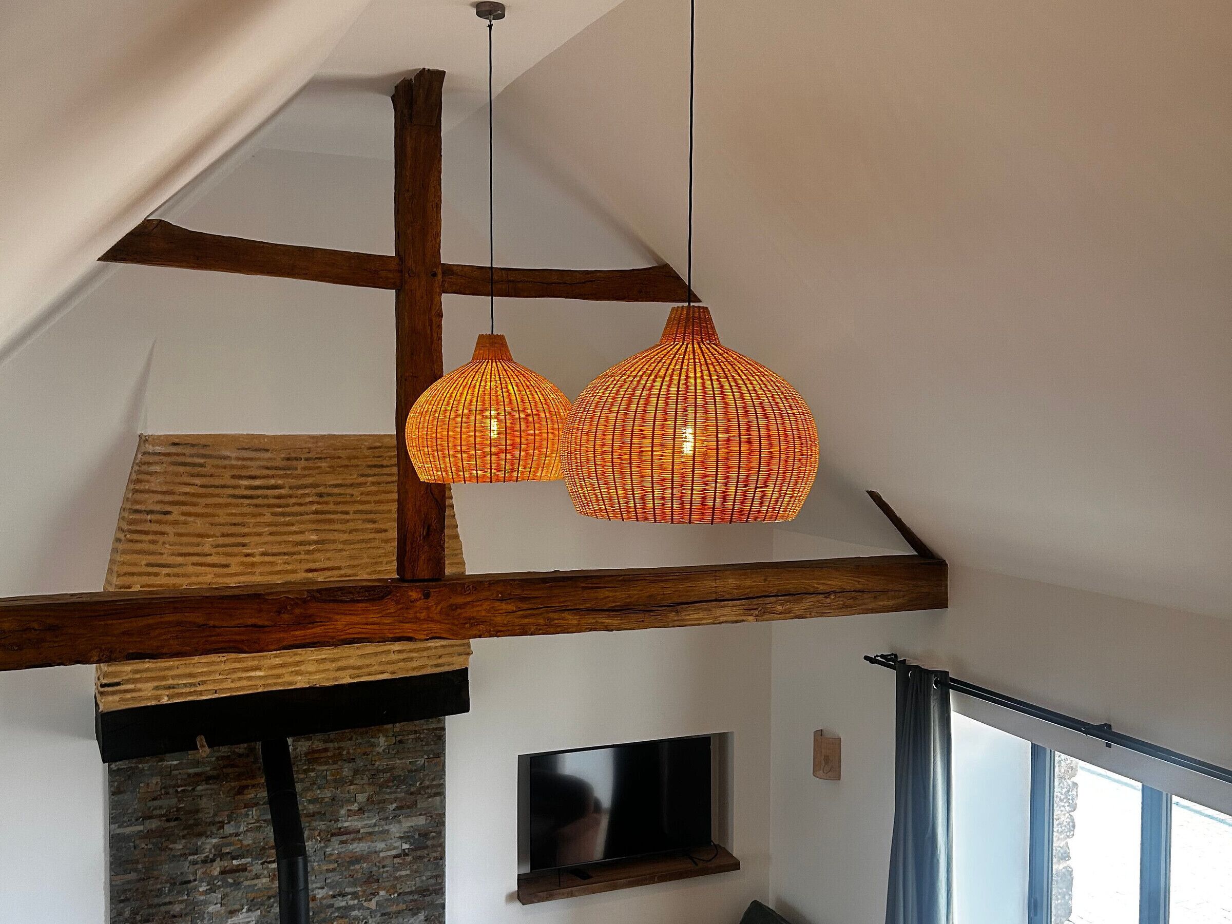 Een loft-stijl kamer met zichtbare houten balken, een stenen openhaard en een groot raam.