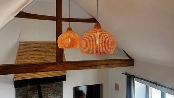 Een loft-stijl kamer met zichtbare houten balken, een stenen openhaard en een groot raam.