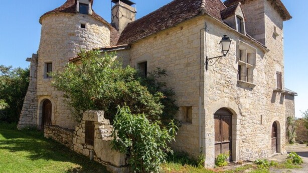 Edificio de piedra con una torre, ventanas de arco y un farol.