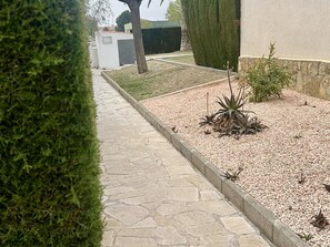 Ein gepflasterter Weg führt zu einem Gebäude mit einem kleinen Garten.