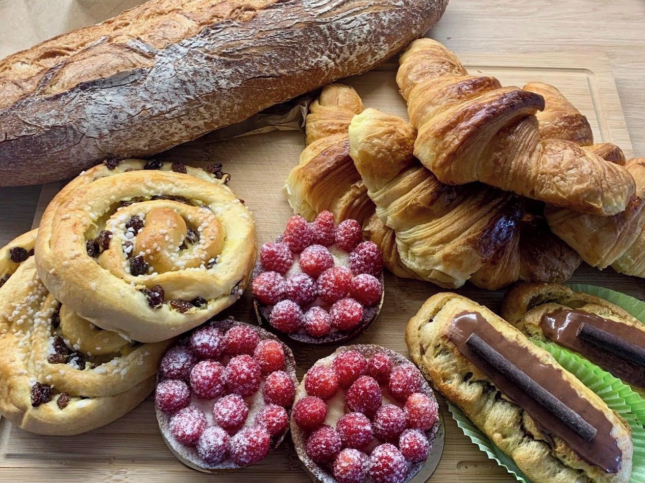 Verschiedene Backwaren, darunter Brot, Croissants und Gebäck mit sichtbaren Füllungen und Belägen.