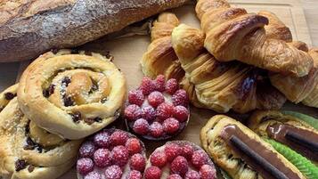 Verschiedene Backwaren, darunter Brot, Croissants und Gebäck mit sichtbaren Füllungen und Belägen.