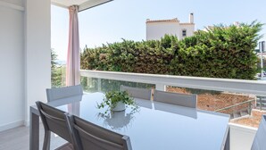 Een balkon met een witte reling, een tafel met stoelen en een potplant.