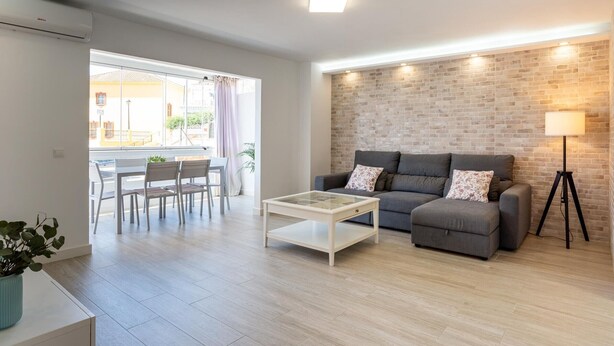 Een moderne woonkamer met een bank, salontafel en een eetgedeelte met stoelen en een tafel.