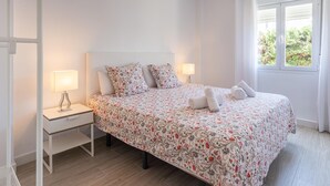 Een slaapkamer met een bed, twee nachtkastjes, een lamp, een hanglamp en een raam met uitzicht.