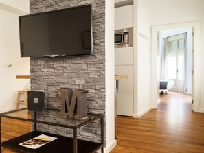 A modern living room with a stone wall, a mounted TV, and a glass coffee table with a magazine. - Modern Apartment in Malaga with Wi-Fi near Plaza de la Merced (Málaga)
