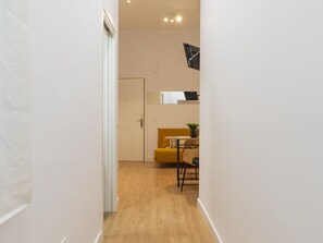 A hallway leading to a room with a yellow sofa, a small table, and a clock on the wall. - Quiet apartment in Malaga city center ideal for couples (Málaga)