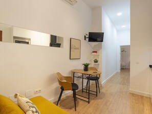 A modern living room with a sofa, a small table with two chairs, a TV mounted on the wall, and a framed picture. - Quiet apartment in Malaga city center ideal for couples (Málaga)
