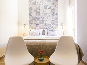 A hotel room with a bed, two chairs, a small table with a vase, and a patterned wall. - Elegant apartment in Malaga city center, close to the beach (Málaga)