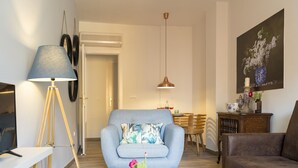 Un soggiorno moderno con un divano, un tavolino, una lampada e un'area pranzo sullo sfondo.