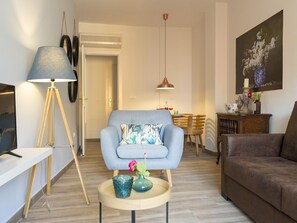 A modern living room with a sofa, a coffee table, a lamp, and a dining area in the background. - Elegant apartment in Malaga city center, close to the beach (Málaga)