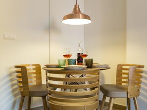 A round wooden table with two chairs, a hanging pendant light, and a bottle of wine on the table. - Elegant apartment in Malaga city center, close to the beach (Málaga)