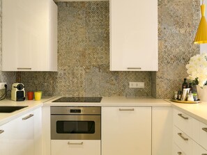 A modern kitchen with white cabinets, a stainless steel oven, and a granite backsplash. - Elegant apartment in Malaga with rooftop pool (Málaga)