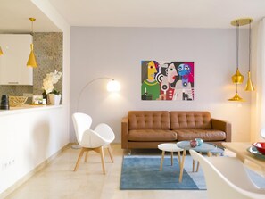 A modern living room with a brown sofa, white chairs, a coffee table, and a painting on the wall. - Elegant apartment in Malaga with rooftop pool (Málaga)