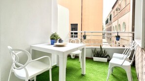 A small balcony with a white table and chairs, green artificial grass, and potted plants. - Bright apartment at Malagueta beach with private terrace (Málaga)