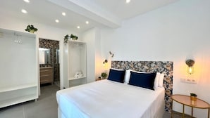 A modern bedroom with a large bed, a walk-in closet, and a small round table. - Bright apartment at Malagueta beach with private terrace (Málaga)